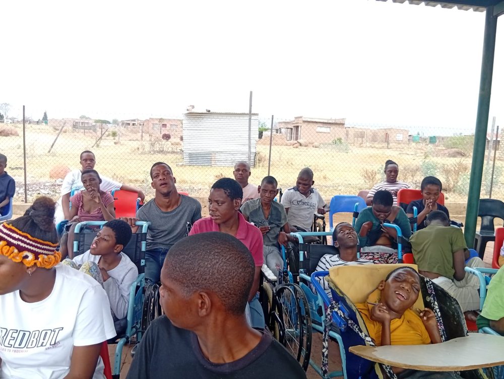 Children and young adults gathered under the shade at the centre